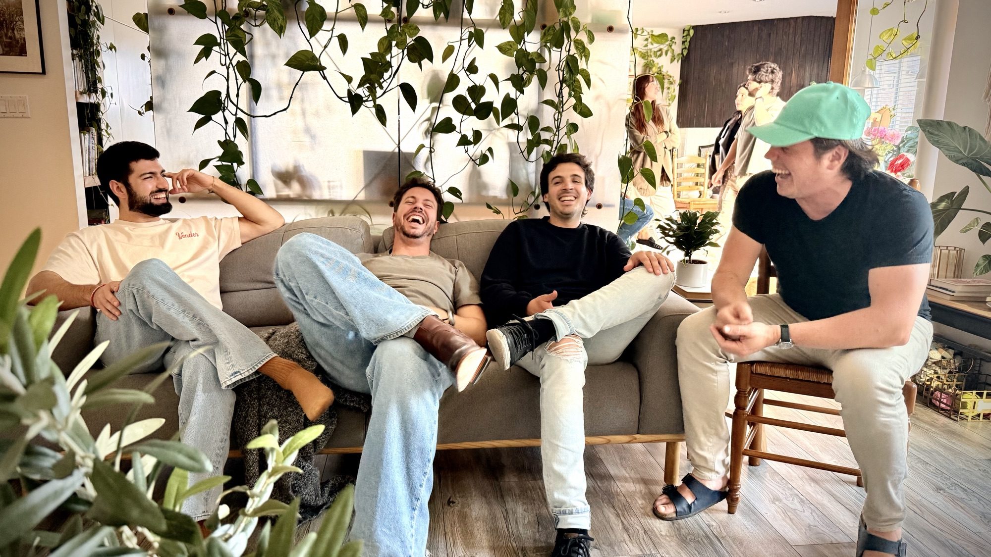 Four friends cracking up on a couch on a sunny afternoon