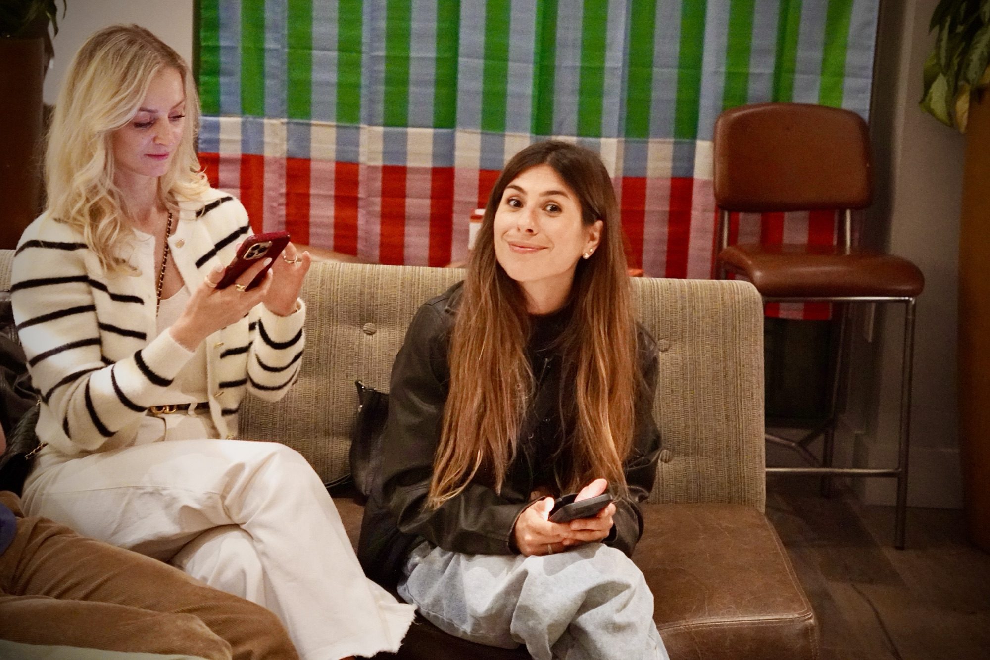 Two newcomers smiling over their phones