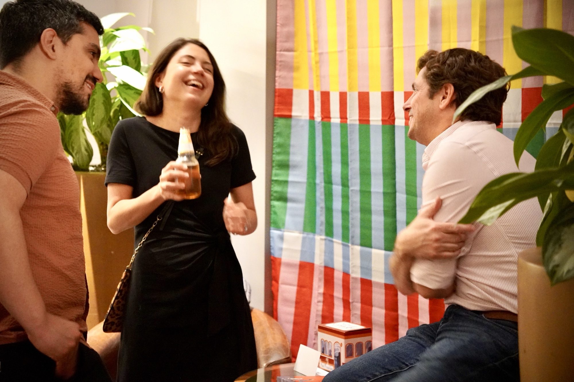 Friends laughing against a colorful striped wall